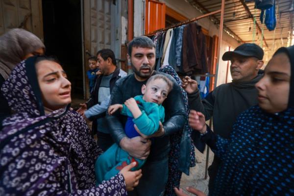 A Palestinian man holds a child as they flee following the resumption of Israeli bombardment in Rafah