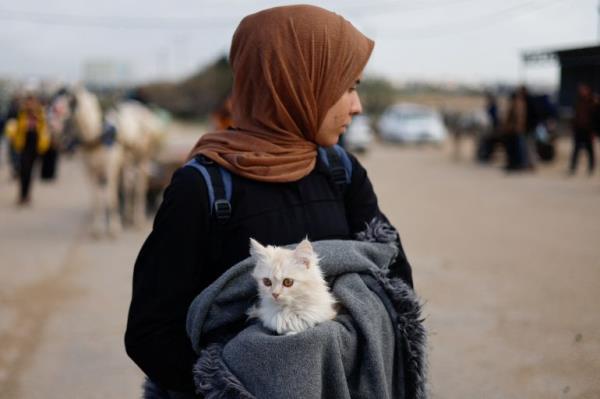 A woman holds a cat as Palestinian arrive in Rafah