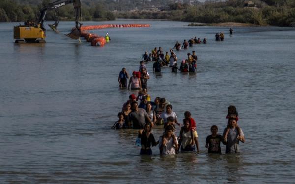 A line of migrants crossing the Rio Grande river to enter into Eagle Pass on July 27, 2023.