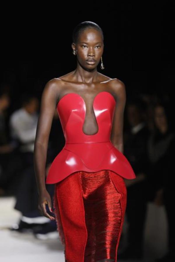 Alexander McQueen model in red, structured peplum top on runway