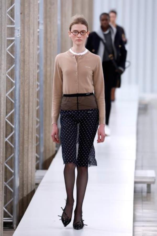 Miu Miu runway model wearing mesh skirt and beige sweater