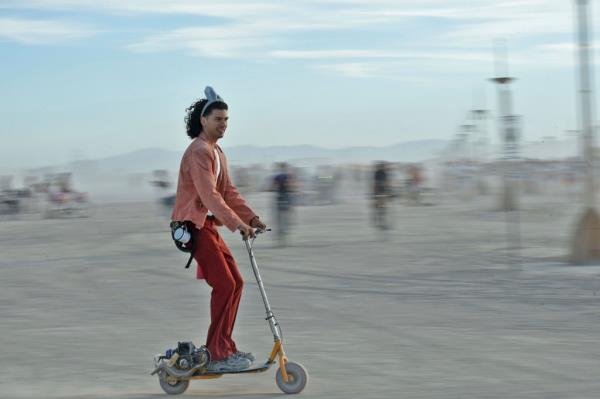 Man on scooter wearing a headband at Burning Man. 