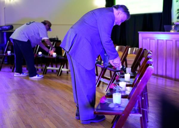 DeAngelis lights candles on 13 empty seats representing the victims of the Columbine shooting at a vigil held Friday night.