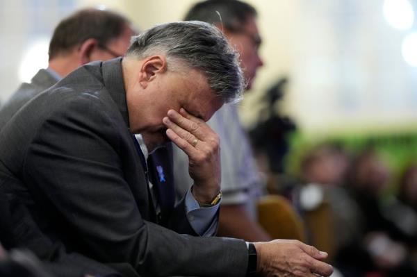 DeAngelis leans forward with a hand over his eyes during the Friday night vigil.