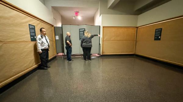 Former exhibit dedicated to Native American artifacts seen emptied with brown paper ining the walls. Staff seen in background