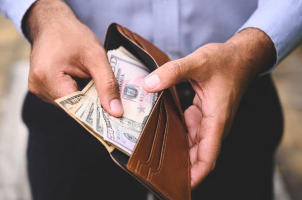 Close-up of a businessman counting a spread of cash in his wallet.