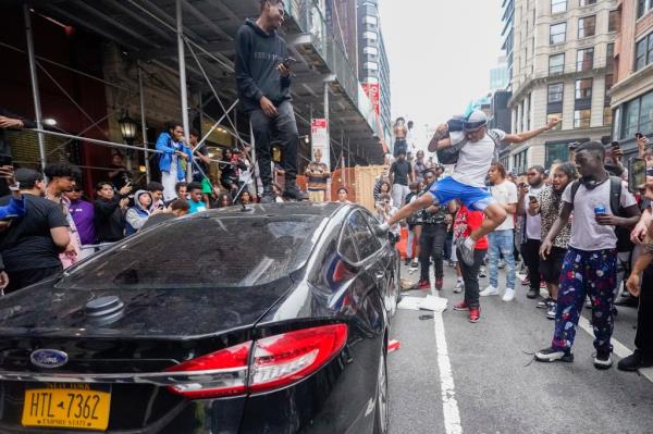 A demo<em></em>nstrator jumps on the top of a car as kicks in the window near Unio<em></em>n Square park, Friday, Aug. 4, 2023