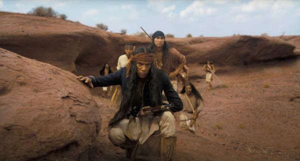 Native Americans crouching in dirt. 