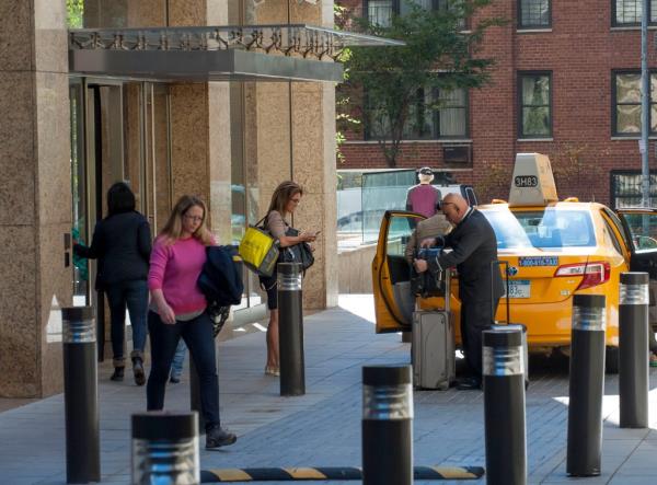 A man exiting a taxi with suitcases.