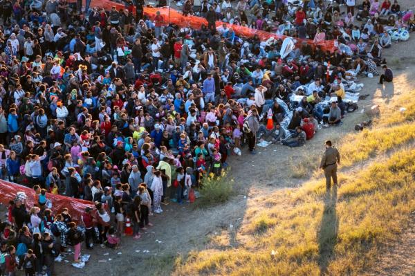 A US Border Patrol agent watches over migrants waiting to be processed after crossing from Mexico into the United States on December 17, 2023 in Eagle Pass, Texas