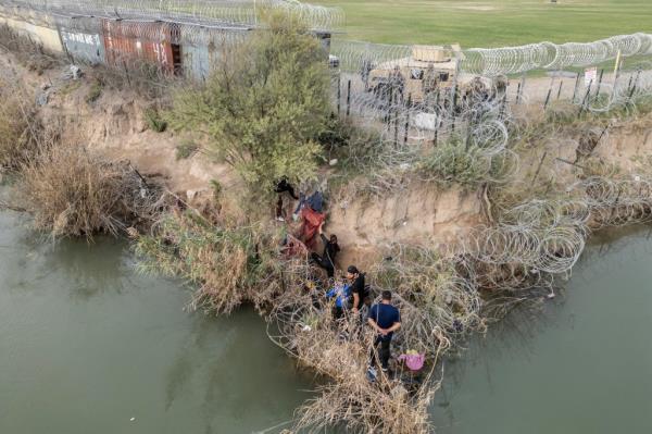 A group of migrants attempt to go through a wire fence on the banks of the Rio Grande river as members of U.S. Natio<em></em>nal Guards stand guard on the other side of the fence in Eagle Pass, Texas, U.S., February 27, 2024