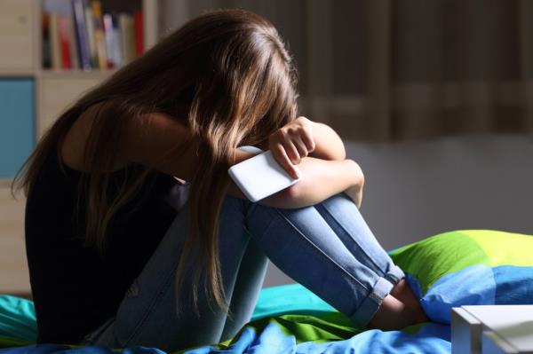 Single sad teen holding a mobile phone 