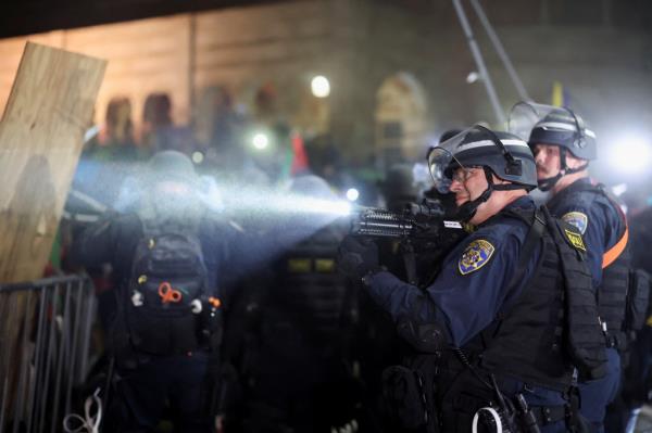 Law enforcement officers hold weapons as they storm the encampment at UCLA.