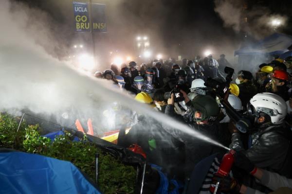 Demo<em></em>nstrator aiming a fire extinguisher at law enforcement officials during a protest in support of Palestinians at the University of California Los Angeles