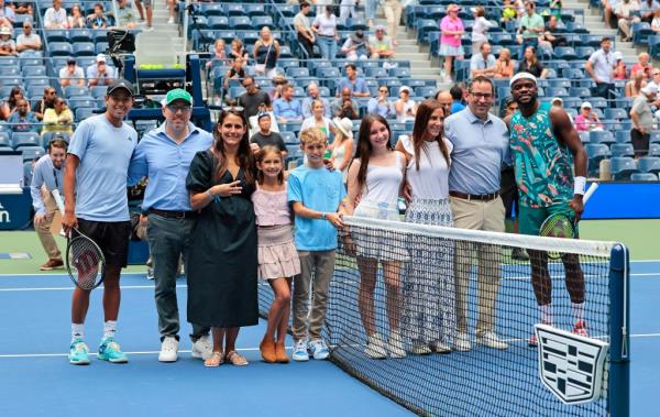 Gary Falkowitz (left), father of Ethan Falkowitz, and Mitchell Hassenbein (right), father of Drew Hassenbein, on the court of Arthur Ashe Stadium with their families for the coin toss before Frances Tiafoe and Learner Tien match. 