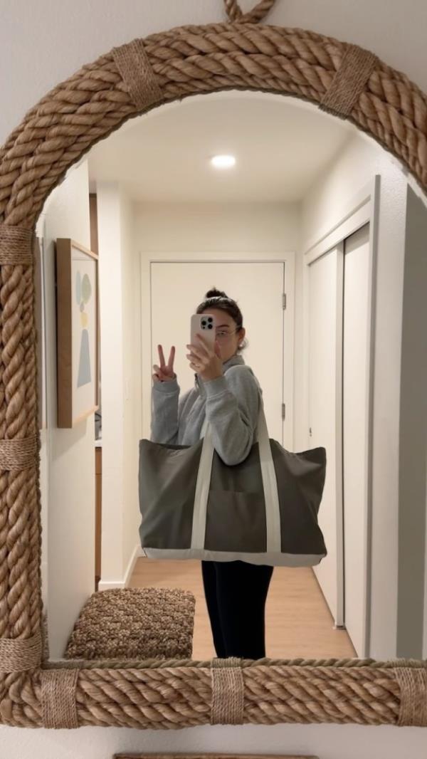 A $120 tote bag displayed on a mirror with Mariko taking a selfie reflected in it