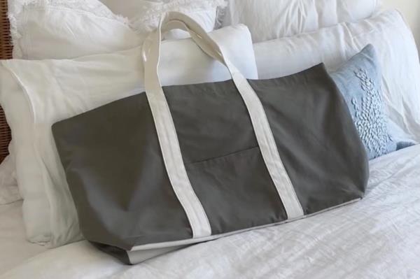 Gray tote bag resting on a bed with soft lighting.