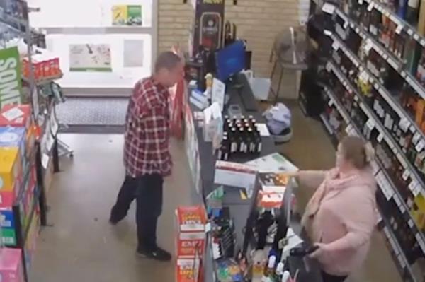 Man in red flannel places box o<em></em>nto counter of liquor store.