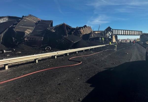 In this photo released by the Pueblo County Sheriff's Office, police respond to the scene of a train derailment near Pueblo, Colo., Sunday, Oct. 15, 2023. The train derailment Sunday spewed coal and mangled train cars across the highway. (Joshua Johnson/Pueblo County Sheriff's Office via AP)