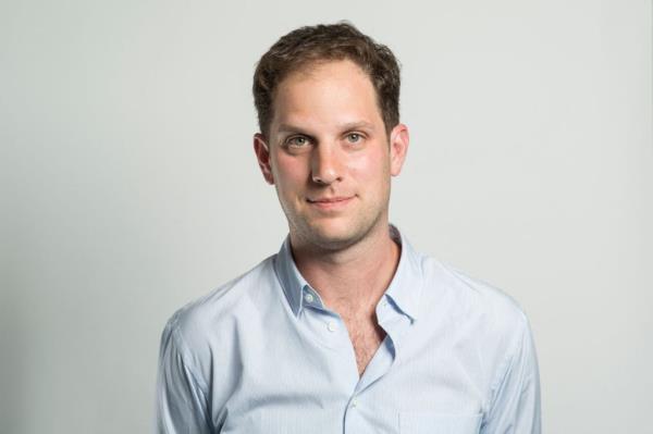 profile shot of evan gershkovich, wearing a light blue collared shirt