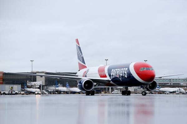 Red, white and blue painted Patriots airplane sitting on tarmac at airport.