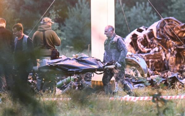 Worker carries body bag from site