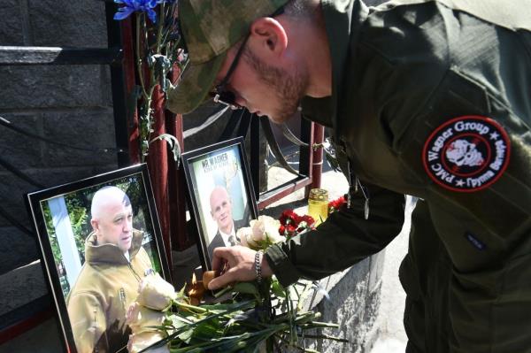 A member of private mercenary group Wagner pays tribute to Yevgeny Prigozhin (L) and Dmitry Utkin, a shadowy figure who managed Wagner's operations and allegedly served in Russian military intelligence, at the makeshift memorial in front of the PMC Wagner office in Novosibirsk, on August 24, 2023. 