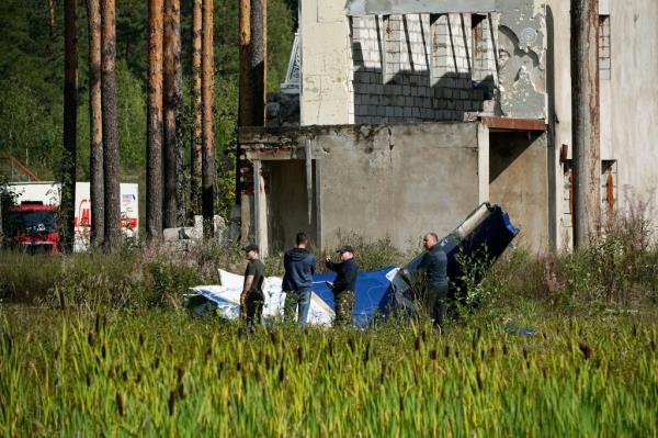 Russian servicemen inspect a part of a crashed private jet near the village of Kuzhenkino, Tver region, Russia, Thursday, Aug. 24, 2023. 