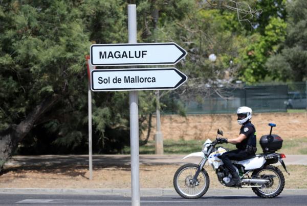 A motorcycle cop rides past a signpost to Magaluf and Sol de Mallorca.