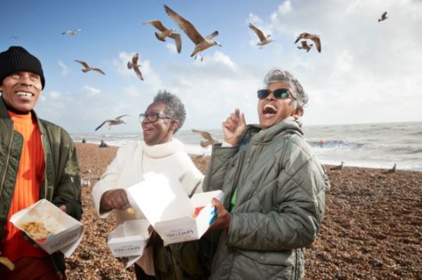 Friends eating fish and chips on beach 