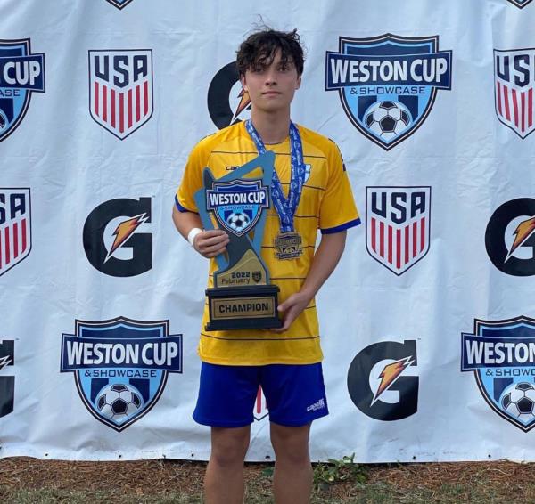 A photo of the late Tim Schmidt Jr. posing with a soccer trophy.