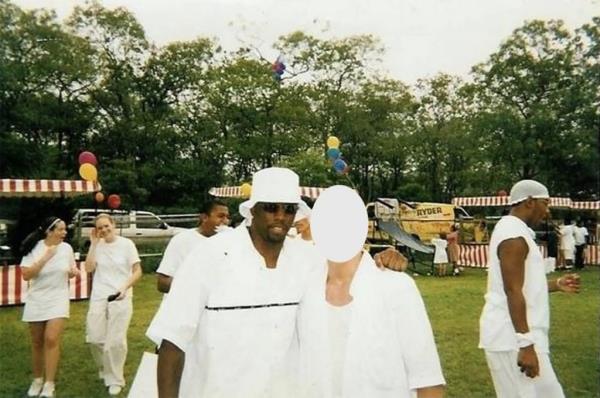 Sean 'Diddy' Combs wearing a white bucket hat and T-shirt, draping arm around an obscured-face youngster at a Hamptons white party in 1998