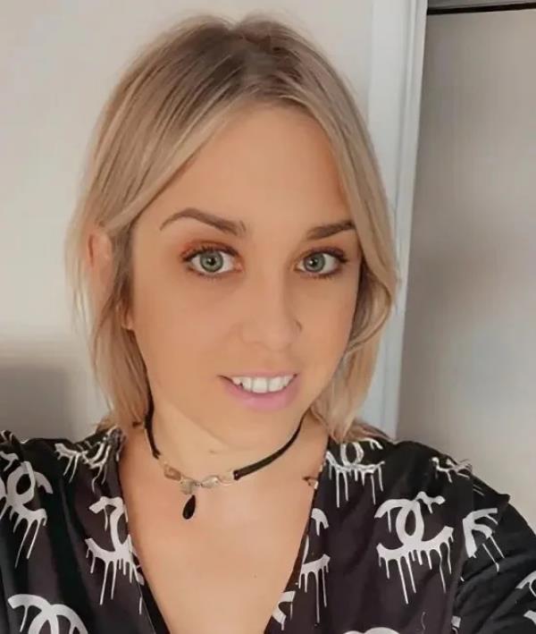 A woman wearing a black Chanel shirt and a choker smiles