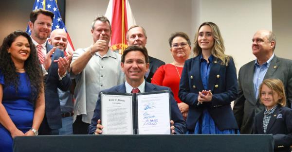 Florida Gov. Ron DeSantis smiles as he holds up House bill 621 