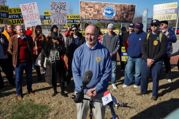 UAW President Shawn Fain speaking to the media in front of a microphone after visiting the Volkswagen plant in Chattanooga, Tennessee in December 2023