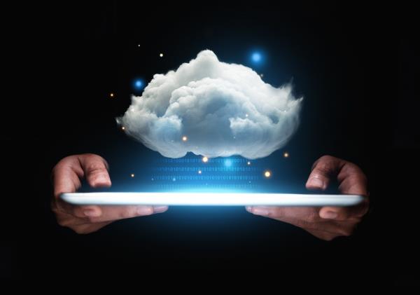 Businessman's hand holding a tablet displaying cloud computing concept, symbolizing AI advancements and potential job losses.