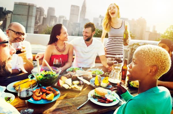 A group of diverse friends socializing at a table with food and drinks