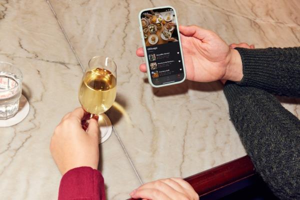 A person holding a phone and a glass of wine at Resy Bar Americano