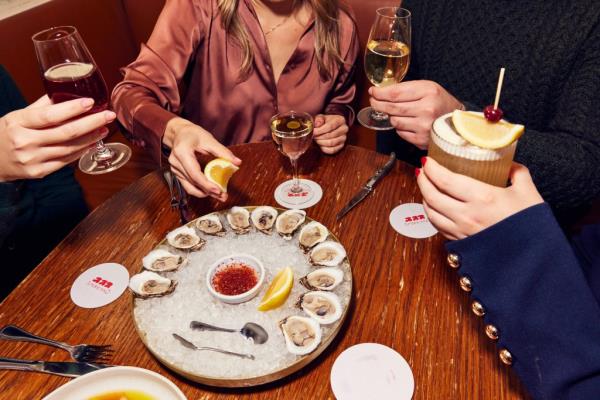 A group of people sitting at a table with food and drinks at Resy Bar Americano