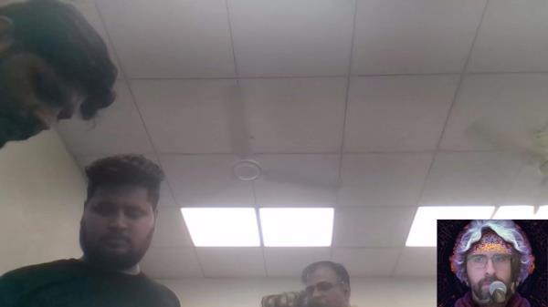 Three men seen in an office in a still fro YouTube. Most of the picture is the white tile ceiling. In the bottom right is the YouTube narrator's avatar.