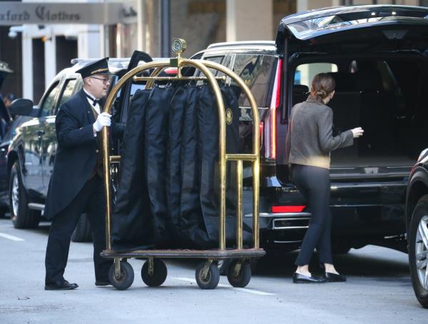 A Trump Tower doorman helps to load Melania's luggage into a parked SUV.